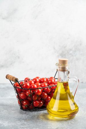 Red cherry tomatoes with a bottle of extra virgin olive oil on marble backgroundの写真素材