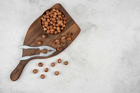 Wooden bowl of unpeeled organic hazelnut kernels on cutting boardの写真素材