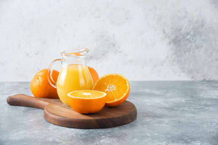 A wooden board full of juicy slices of orange fruit on stone background