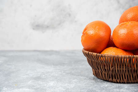 A wicker box full of juicy orange fruits on stone backgroundの写真素材