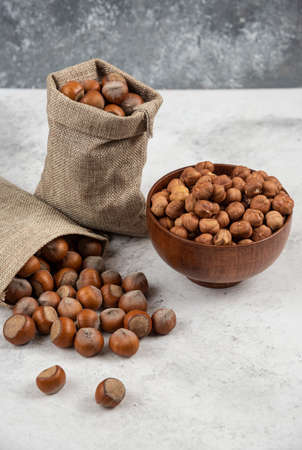 Pile of organic shelled and kernels of hazelnuts in burlap and in bowl
