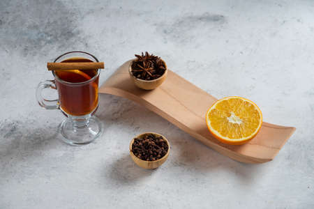 A cup of tea with slice of orange and dried loose teas