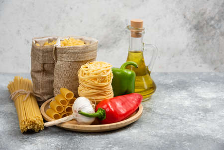 Raw pasta varieties with garlic, chili peppers and olive oilの写真素材