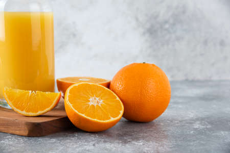 Glass pitcher of juice with fresh orange fruits on a wooden boardの写真素材