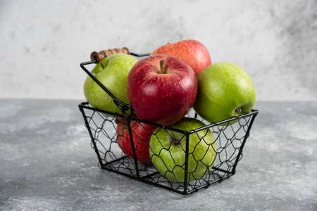 Bunch of fresh green and red apples placed in metal basketの写真素材