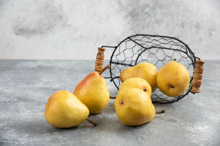 Pile of fresh yellow pears in metal bucket on marble surfaceの写真素材