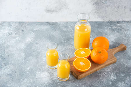 Glass pitcher of juice with sliced orange fruit on a wooden boardの写真素材