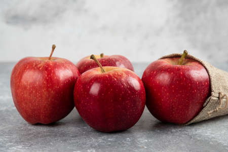 Delicious red apples out of burlap on marble backgroundの写真素材
