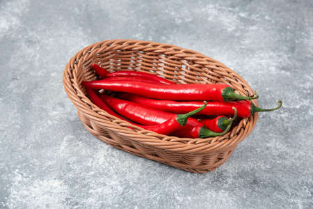 Wicker basket of red chili peppers on marble surfaceの写真素材