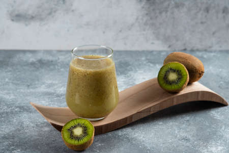 A glass cup of delicious kiwi juice on a wooden boardの写真素材