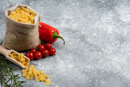 Pasta basket with red chili, tomatoes and rosemary on a marble backgroundの写真素材