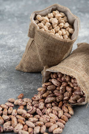 Sackcloth of organic raw beans placed on marble surface