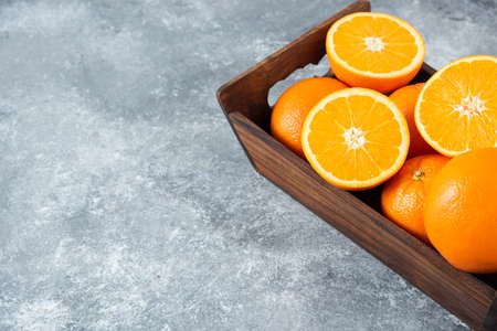 A wooden old box full of sliced and whole juicy orange fruitsの写真素材