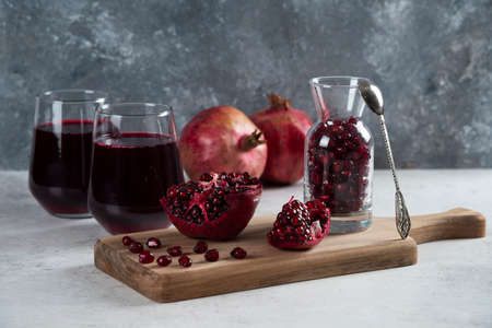 A small jar full of pomegranate and cups of juiceの写真素材