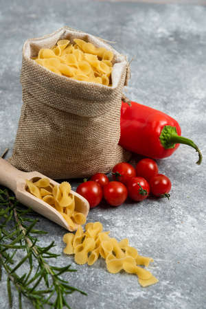 Pasta basket with red chili, tomatoes and rosemary on a marble background