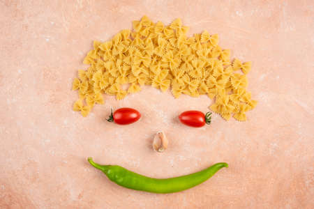 Scattered farfalle pasta with vegetables on orange backgroundの写真素材