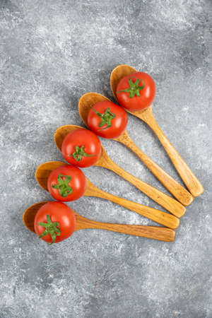 Wooden spoons of red fresh tomatoes on marble backgroundの写真素材