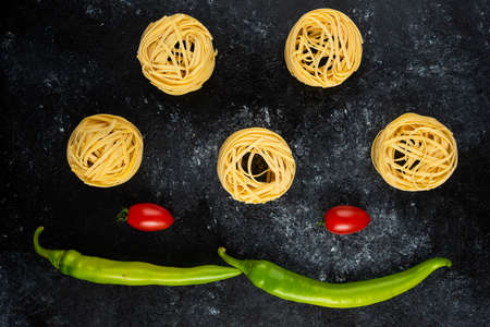 Uncooked pasta nests and vegetables on marble backgroundの写真素材