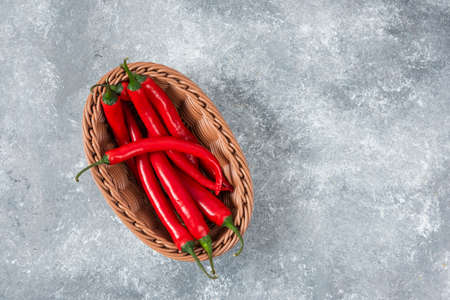 Wicker basket of red chili peppers on marble surfaceの写真素材