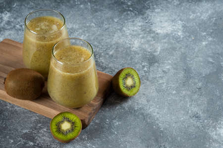 Two glass cups of tasty kiwi juice on a wooden boardの写真素材