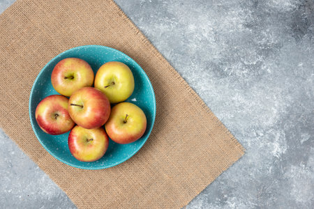Blue bowl full of fresh apples on marble backgroundの写真素材