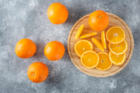 A wooden board full of juicy slices of orange fruit on stone backgroundの写真素材