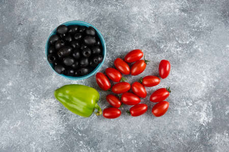 Black olives, pepper and tomatoes on marble backgroundの写真素材