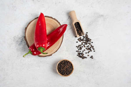 Hot chili peppers and pepper grains on marble background
