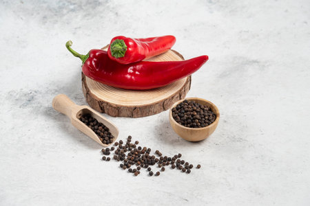 Hot chili peppers and pepper grains on marble backgroundの写真素材