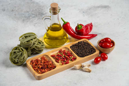 Green tagliatelle, dry spices and olive oil on marble backgroundの写真素材