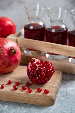 Fresh red pomegranates on wooden board with juiceの写真素材