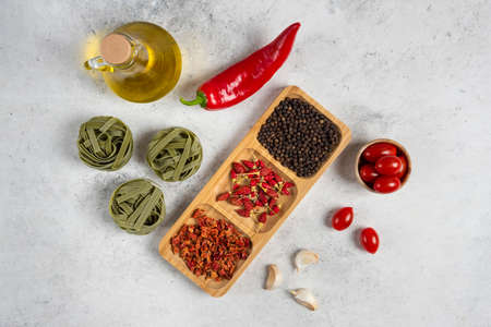 Green tagliatelle, dry spices and olive oil on marble backgroundの写真素材