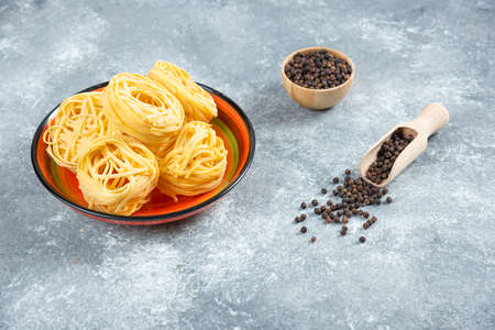 Plate of noodles and pepper grains on marble backgroundの写真素材
