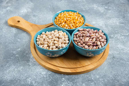 Raw corns, beans and chickpeas in blue bowlsの写真素材