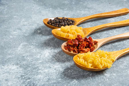Wooden spoons of raw pasta on marble backgroundの写真素材
