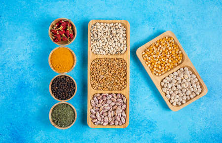 Variety of spices and raw beans on blue backgroundの写真素材
