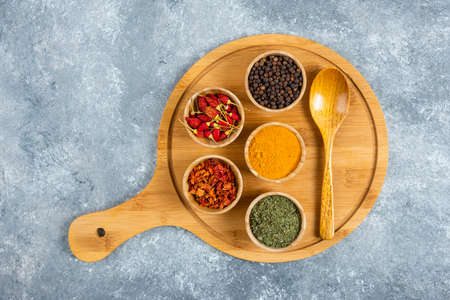 Bunch of spices with spoon on wooden boardの写真素材