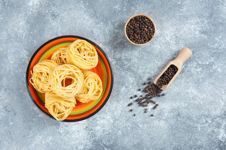 Plate of noodles and pepper grains on marble backgroundの写真素材