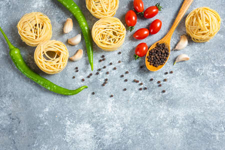 Spaghetti nests, peppers and tomatoes on marble backgroundの写真素材