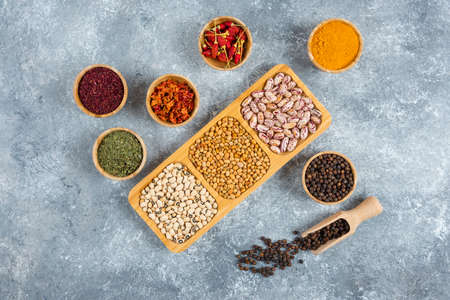 Plates of raw beans and spices on marble backgroundの写真素材