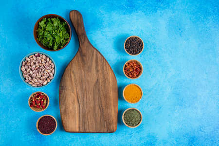 Variety of spices, vegetables and raw beans on blue background