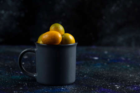 Black cup full with organic tasty kumquatsの写真素材