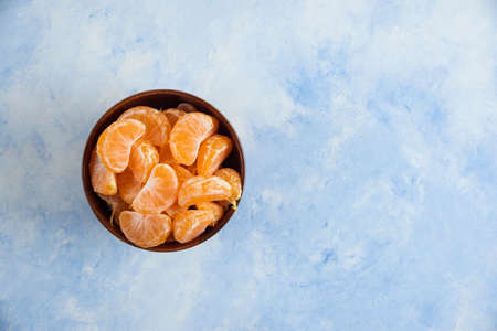 Mandarin slices in wooden bowl on blue backgroundの写真素材