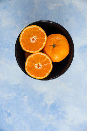 Vertical photo of clementine in black ceramic bowlの写真素材