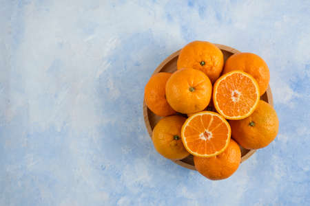 top view. Pile of clementine mandarins on wooden plate over blue backgroundの写真素材