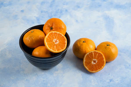 Clementine mandarins in bowl on blue backgroundの写真素材