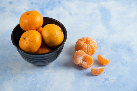 Close up photo of Clementine mandarins whole or peeled in black bowl. High quality photoの写真素材