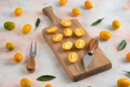 Pile of kumquats, Whole or half cut on wooden cutting boardの写真素材