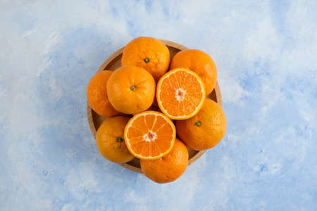 Top view. Pile of clementine mandarins on wooden plate over blue backgroundの写真素材