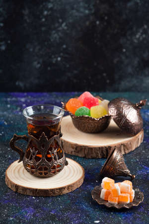 Vertical photo of colorful candies and fragrant tea on blue backgroundの写真素材